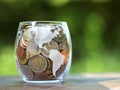 euro coins collected for vacation in glass jar with america map inprint, green blured background