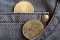 Euro coins with a denomination of 20 and 50 euro cents in the pocket of worn brown denim jeans
