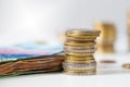 Euro coins stacked in pile and heap of bank notes lying on white table