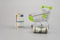 Euro and dolar banknotes in rolls with supermarket trolley on gray background Royalty Free Stock Photo