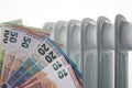 Euro money banknotes on heating radiator battery. Concept of expensive heating costs and rising energy bill Royalty Free Stock Photo