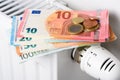 Euro money banknotes on heating radiator battery with thermostat temperature regulator.