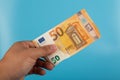 50 Euro note on hand on blue background