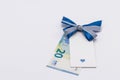 A 20 euro paper banknote and a gift tag decorated with a blue bow on a white background. Free space for copying. The concept of a Royalty Free Stock Photo