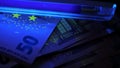 Euro under ultraviolet light. Detecting fake banknotes.