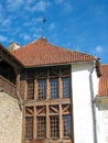 Europe. Part of the old medieval building: the roof covered by red shingles and wooden frame for windows, and white wall of the ho Royalty Free Stock Photo