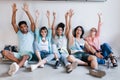 European, asian and african students celebrating the end of examination. Friends sitting on the floor in college and