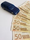 european banknotes and figure of a car in dark blue