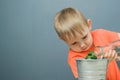 European blond boy child watering young money tree plant