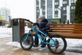 European boy dressed in a winter jacket is tired of riding a bicycle Royalty Free Stock Photo