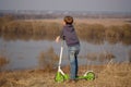 European boy with scooter on the high Bank of the river