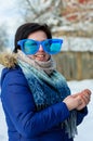 European brunette girl in big clown glasses with scarf, smiling, standing alone rubbing his hands in cold winter Royalty Free Stock Photo