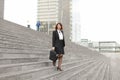 European businesswoman going down on stairs in high buildings background.