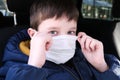 A european caucasian teenage boy in car putting on white protective surgical medical face mask as a protection against virus Royalty Free Stock Photo