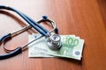 European currency sick concept: stethoscope on euro banknotes. on wooden table background. Health care concept Royalty Free Stock Photo