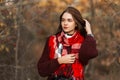 European cute young woman model woman in a bordo trendy knitted sweater with a warm checkered scarf posing in a forest on a