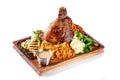 European, Czech cuisine. Pork knuckle on a wooden board with mashed potatoes, stewed cabbage, grilled vegetables and suck