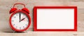 European daylight saving time. Red alarm clock and blank frame isolated on wooden background, banner. 3d illustration