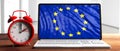 European daylight saving time. Red alarm clock and eu flag on a laptop screen on wooden desk, banner. 3d illustration