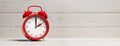 European daylight saving time. Red alarm clock on white wooden background, banner. 3d illustration