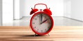 European daylight saving time. Red alarm clock on wooden desk, empty home background. 3d illustration