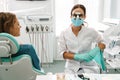 European dentist woman using microscope while working in dental clinic