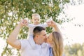 A European family in the park on a summer day. Mom, dad and little son in their arms. Parents kiss each other Royalty Free Stock Photo