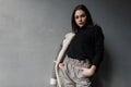 European fashion model of a young woman in gray stylish trousers in a black shirt in a plaid jacket posing standing