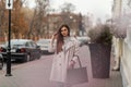 European fashionable woman with beautiful long hair in a stylish trench coat with a vintage leather black bag posing near the road Royalty Free Stock Photo