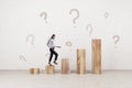 European female climbing abstract wooden plank business chart on concrete wall background with question marks. Financial growth Royalty Free Stock Photo