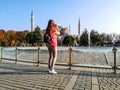 European female tourist shoots Hagia Sophia in Istanbul Turkey on a smartphone, view from the back. Slender girl in trousers and