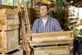 European gardener examines a rack of pallets for planting flower sprouts