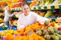 European girl purchaser choosing oranges in a grocery store