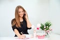 beautiful European girl takes a call on the phone and writes in a notebook on a white background. Nearby are flowers and Royalty Free Stock Photo