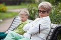 European grandmother and grandson conflict, two people sit in closed poses on bench in park