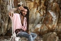 European guy with dreadlocks, asian appearance sitting on a swing on an island, posing