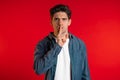 European handsome man holding finger on his lips over red background. Gesture of shhh, secret, silence Royalty Free Stock Photo