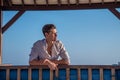 European handsome young man wearing shirt and shorts sitting on the sofa at tropical beach at island luxury resort Royalty Free Stock Photo