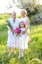 European happy grandmother in white dress with daughter and granddaughter outside.