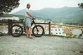 European male cyclist admiring amazing nature standing on top of hill with his motor-powered booster mountain bike