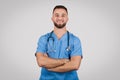 Confident doctor in blue scrubs posing with crossed arms and smiling Royalty Free Stock Photo