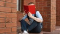 European male student sitting near the library and reading a book Royalty Free Stock Photo