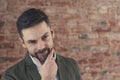 European man in his mid 30s wearing a suit flirtatiously lifting his eyebrow over brick wall background Royalty Free Stock Photo