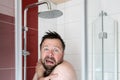 Man in the shower under cold water, he freezes and looks miserable. Energy crisis concept. Royalty Free Stock Photo