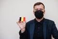 European man wear black formal and protect face mask, hold Belgium flag card isolated on white background. Europe coronavirus Royalty Free Stock Photo