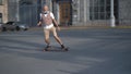 European mid-aged man keeps balance and rushing on a longboard Quickly through sity street.