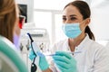 European mid dentist woman in face mask working in dental clinic