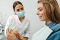 European pleased dentist woman showing teeth imitation to her patient