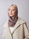 European Muslim woman with a blonde hair in a headscarf shawl dressed on her head. Beautiful girl in coat with soft skin, natural