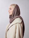 European Muslim woman with a blonde hair in a headscarf shawl dressed on her head. Beautiful girl in coat with soft skin, natural